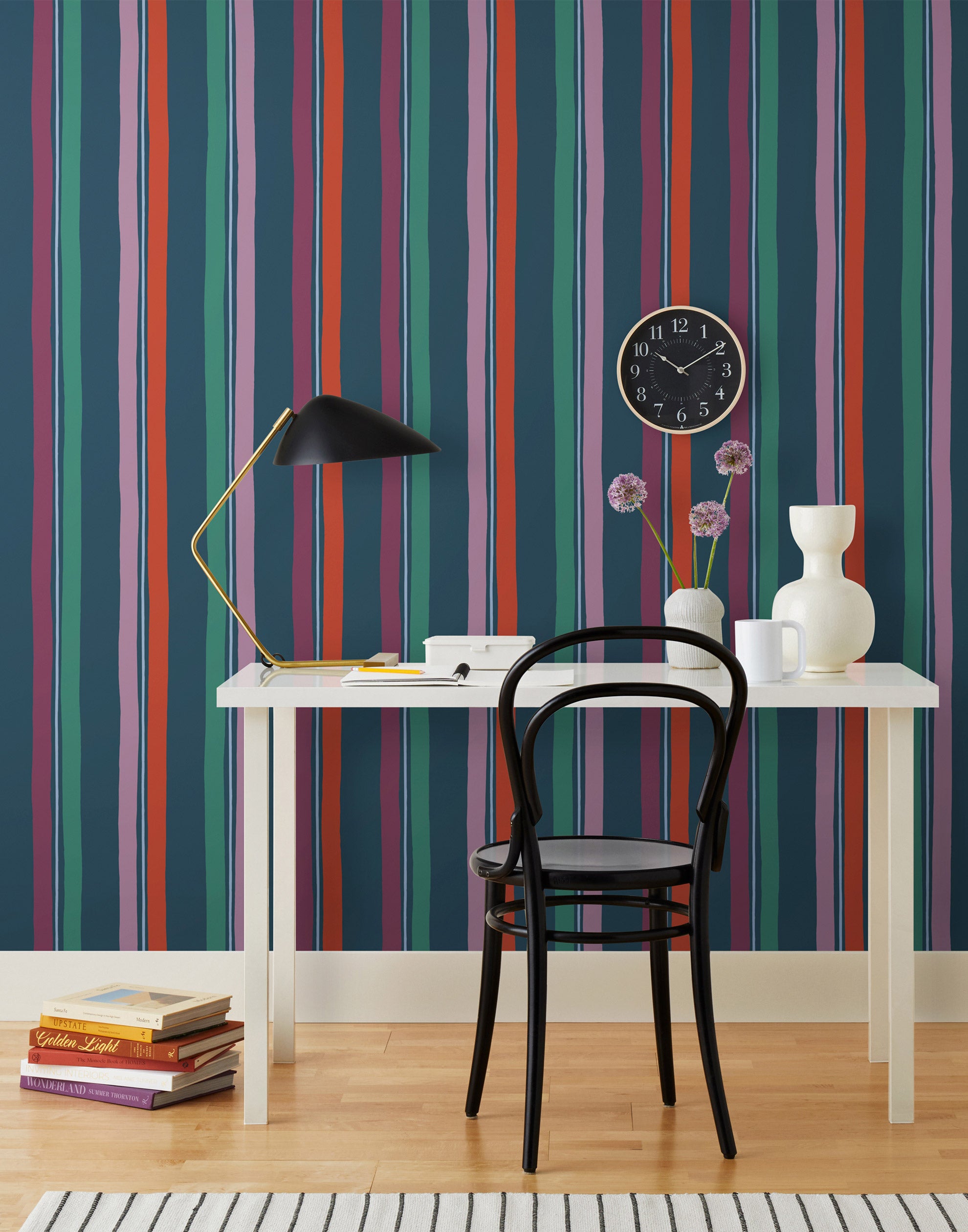 Our Picnic wallpaper was inspired by the wavy stripes of a picnic blanket. Highly durable, fade resistant, and made in the USA. This wallpaper has red, purple, lilac and green stripes on a navy blue background and was made in collaboration with The Aesthetics of Joy.
