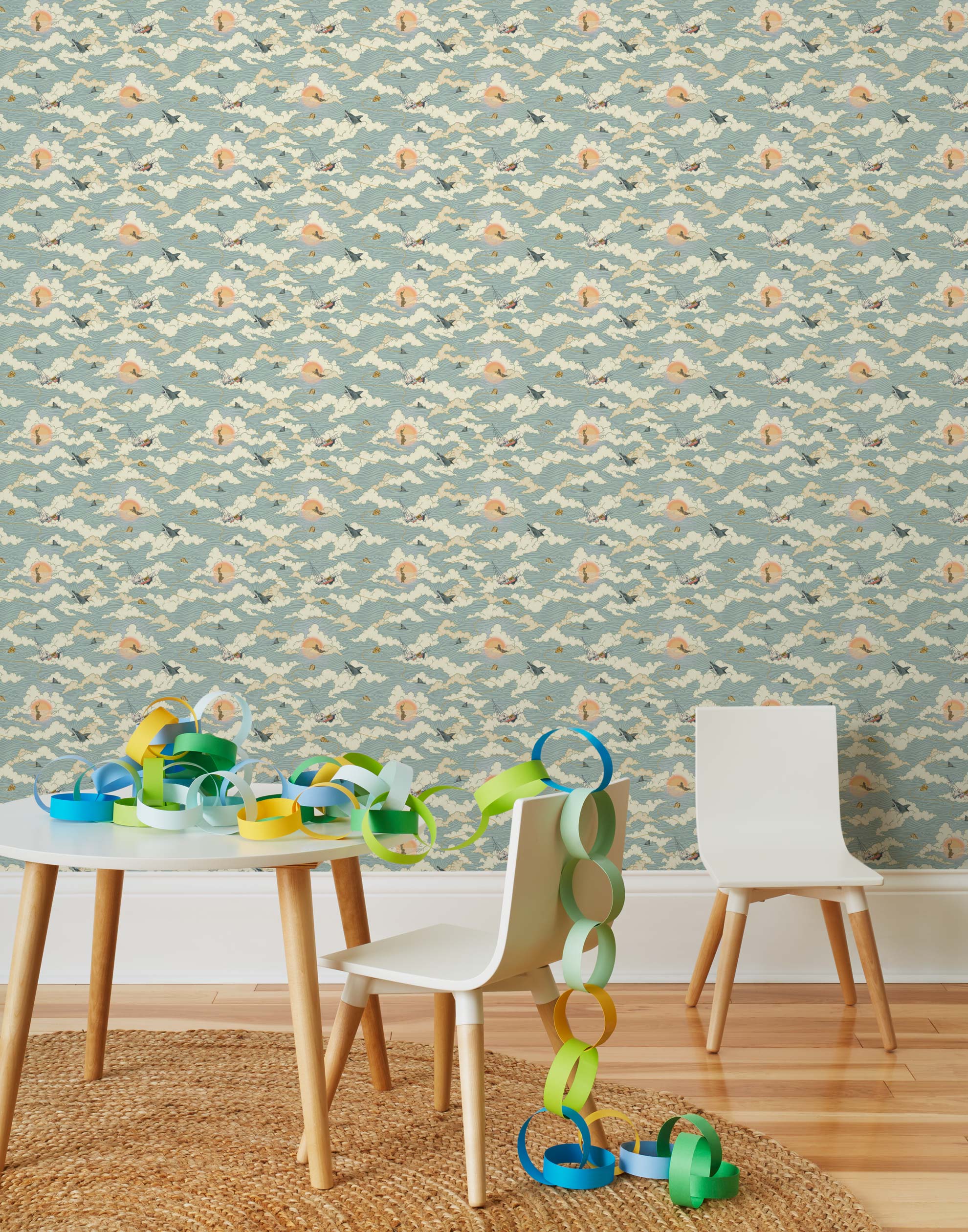 Amity Sunset (Sky) Wallpaper with dusty blue, cream and orange illustrations depicts scenes from the iconic movie Jaws and was created in collaboration with Universal | Hygge & West